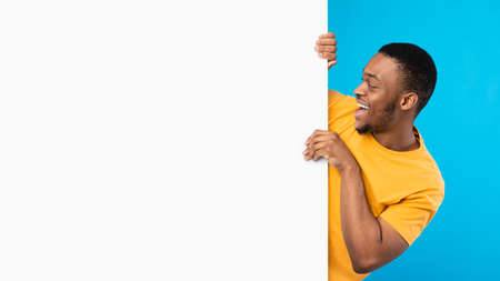 Excited Black Man Looking At Empty White Board, Blue Backgroundの写真素材