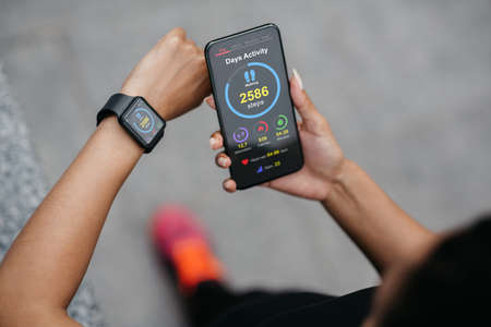 African american lady checking smartphone and smartwatch