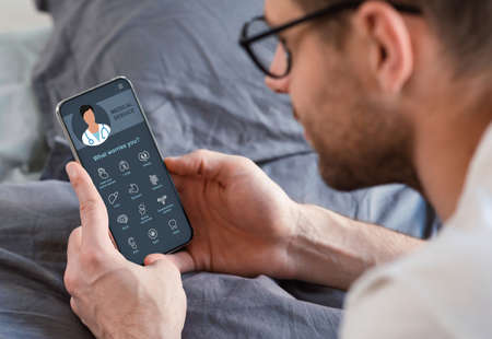 Guy holding mobile phone with online medical service on screen