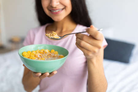 Healthy slimming diet concept. Cropped view of Indian lady with bowl of cereal at home, closeupの写真素材