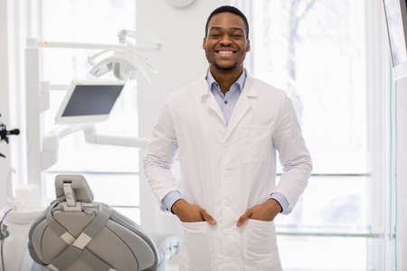 Portrait Of Handsome Young Black Dentist Doctor In Uniform Posing In Clinicの写真素材