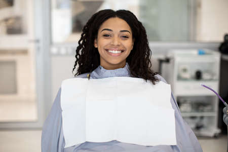 Portrait Of Happy Black Female Patient Sitting In Chair In Dental Clinicの写真素材