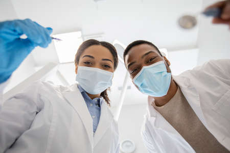 Black Dentist Doctor And His Female Assistant Examinating Patients Teeth, Low Angleの写真素材
