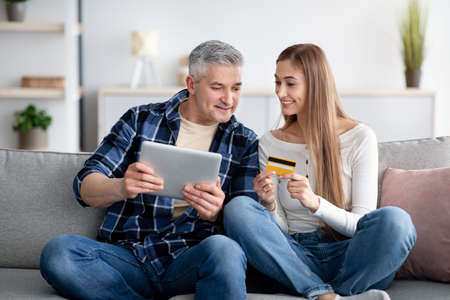 Online shopping concept. Cheerful mature couple using digital tablet and credit card together at homeの写真素材