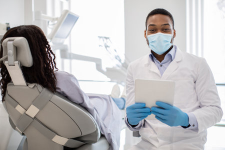 Black Dentist Doctor In Medical Mask Posing At Workplace With Digital Tabletの写真素材