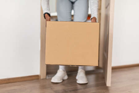 Unrecognizable African American Lady Taking Delivered Box From Floor Indoorの写真素材