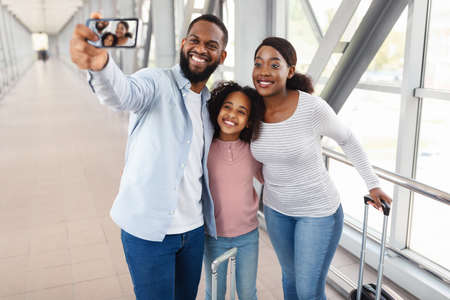 Black family traveling, taking selfie in airportの写真素材