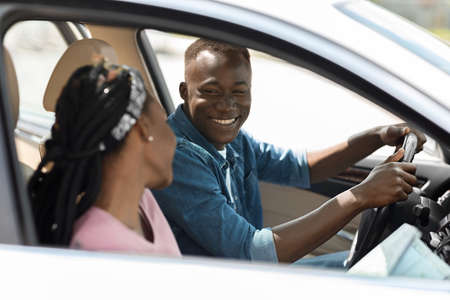 Young black lady helping her husband driver with road map