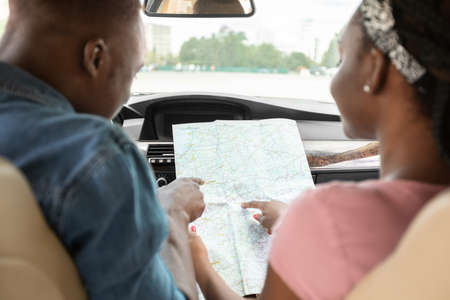 Black couple travellers looking at map while driving, back viewの写真素材