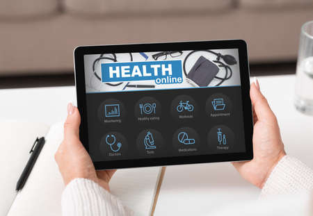 Female hands holding digital pad with online health appの写真素材