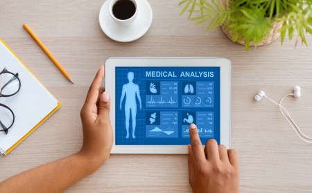 Above view woman using health app on tablet at homeの写真素材