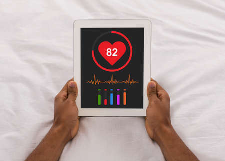 Black man checking his health after waking up, using padの写真素材