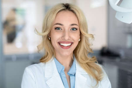 Beautiful woman dentist smiling in dental cabinetの写真素材