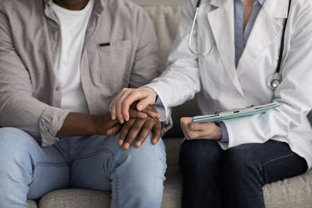 Disabled mature man receiving medical assistance from young caregiver at home