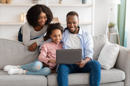 Happy black family using laptop in living roomの写真素材