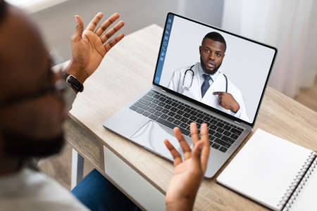 African Businessman Talking To Doc Online, Using Laptopの写真素材