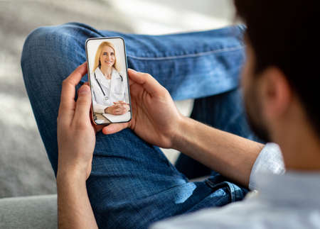 Unrecognizable man using cellphone at home, talking to doctor