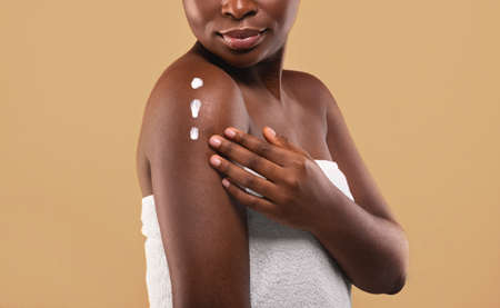Skin Mousturising Concept. Closep Shot Of Young Black Woman Applying Body Lotionの写真素材