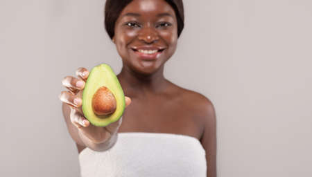 Attractive Young Black Lady With Flawless Skin Showing Avocado Half At Cameraの写真素材