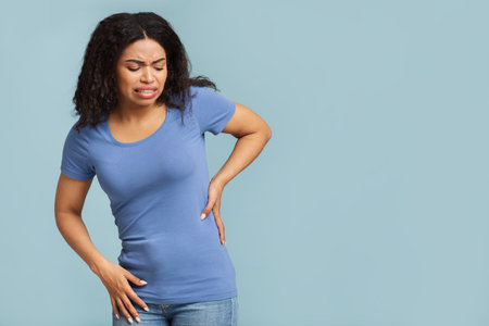 Abdominal pain. African american woman touching left side, suffering from strong stomach ache, blue...
