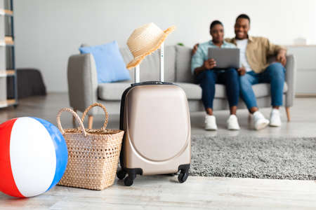 African American Family Using Laptop While Packed Suitcase Lying Indoorの写真素材