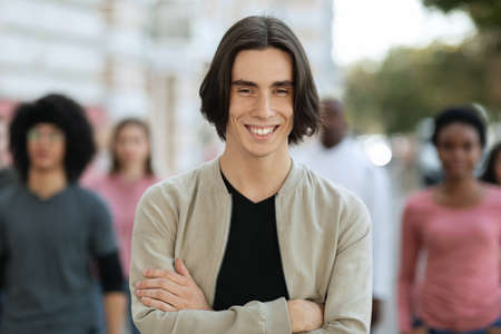 Cheerful young man standing over multiracial crowd on streetの写真素材