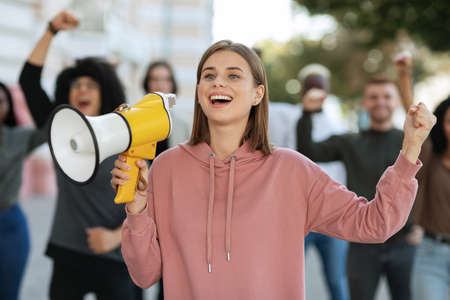 Enthusiastic blonde lady activist with megaphone on the streetの写真素材
