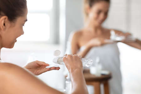 Woman Caring For Skin With Cotton Pad In Bathroom, Back-Viewの写真素材