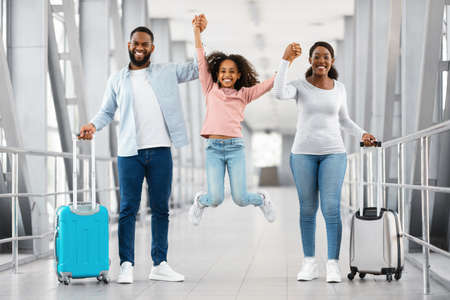 Happy black family traveling with daughter, having fun in airportの写真素材