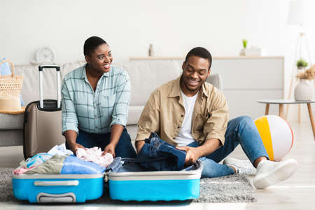 Happy Black Spouses Packing Suitcase Together At Homeの写真素材