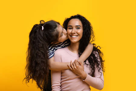 Mothers Day Concept. Adorable Little Girl Embracing And Kissing Her Arab Momの写真素材