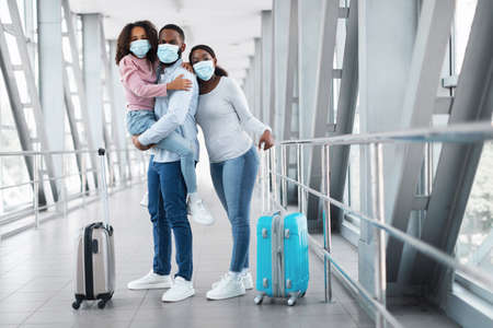 Happy african family traveling with daughter, standing in airportの写真素材