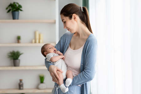 Being A Mother. Young Beautiful Mom Holding Her Newborn Baby In Arms