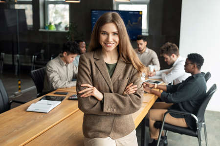 Young businesswoman sitting on desk and posing