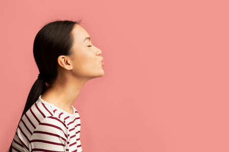 Side View Portrait Of Young Asian Woman Sending Air Kissの写真素材