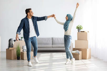 Joyful arab man and woman dancing in their new house