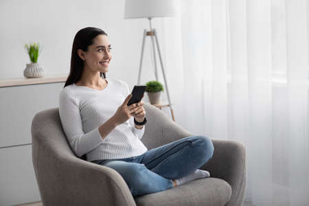 Smiling arab young woman using mobile phone app, playing game, shopping online