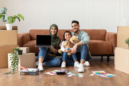 Happy muslim family doing repair woman showing laptopの写真素材