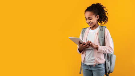 girl standing with tablet at yellow studio wall, panoramaの写真素材