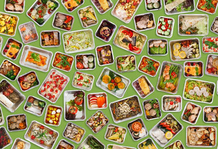 Prepared Everyday Meals In Foil Take Away Containers Over Green Backgroundの写真素材