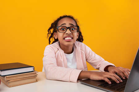 Shocked black girl using laptop and looking at camera