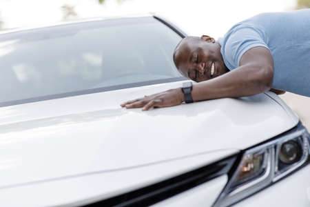 Ecstatic black man leaning on luxury car of his dreamの写真素材