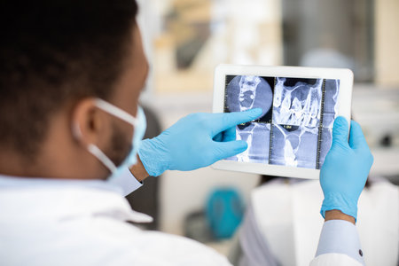 Male Black Dentist Doctor Checking Teeth Xray Picture On Digital Tablet
