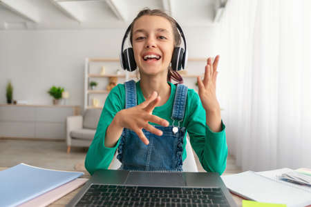 Girl sitting at desk, having video call wearing headset
