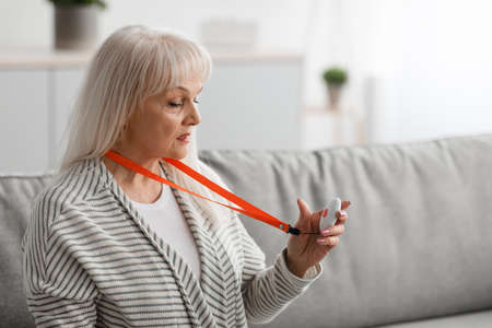 Senior woman holding and using Alarm Button, closeup