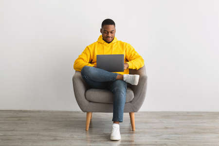 African American Male Freelancer With Laptop Working Online, Gray Backgroundの写真素材