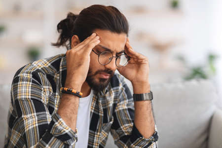 Closeup of sad arab guy touching his head