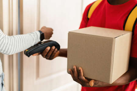 Lady Paying Courier For Parcel Delivery Using Smartwatch Indoor, Croppedの写真素材