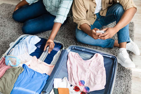 Black Tourists Couple Putting Sanitizer Packing Travel Suitcase At Homeの写真素材