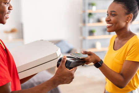 Lady Putting Smartphone To Terminal Paying Courier For Pizza Indoorsの写真素材